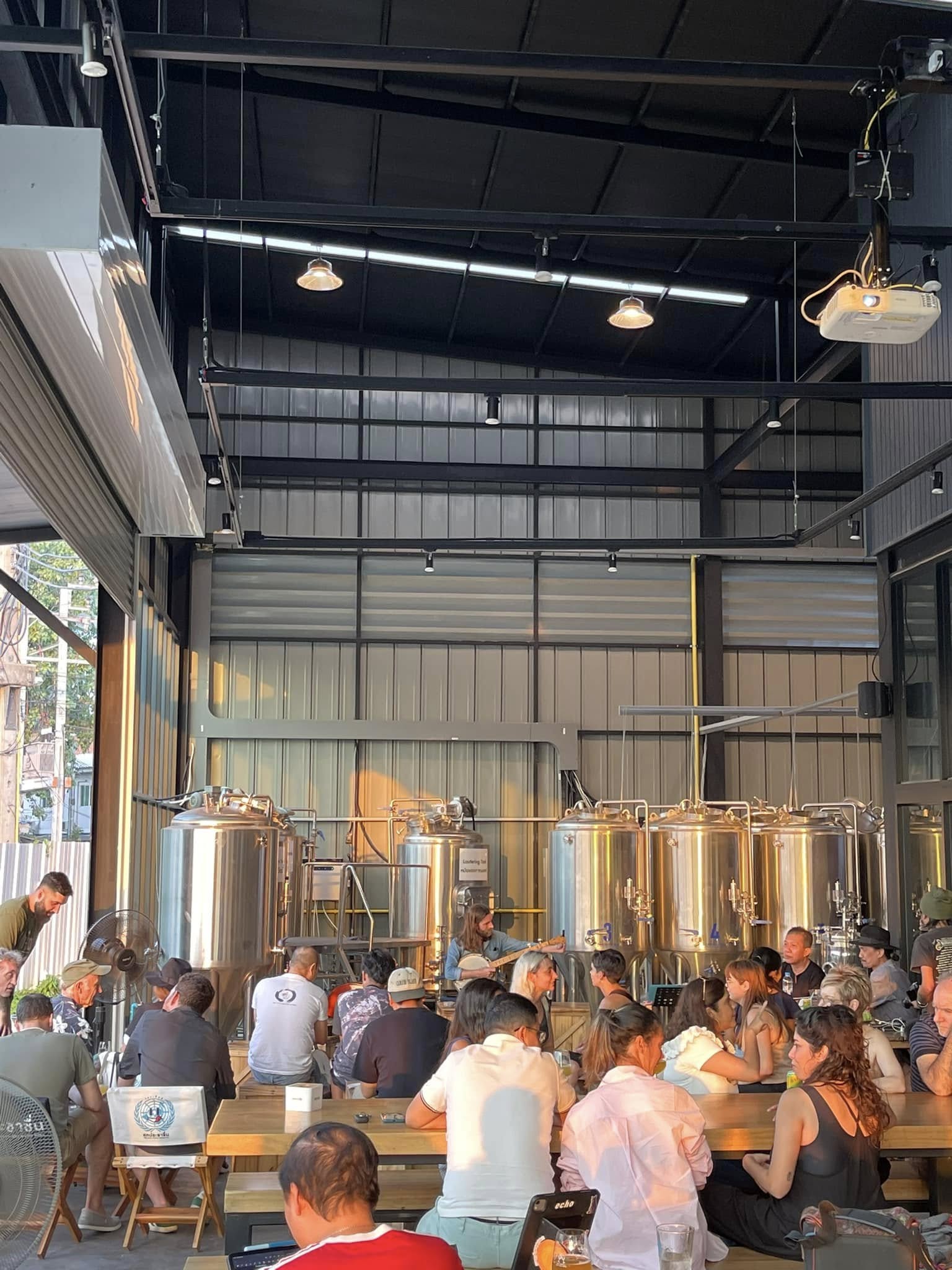 Sandport brewery taproom with guests and fermentation tanks